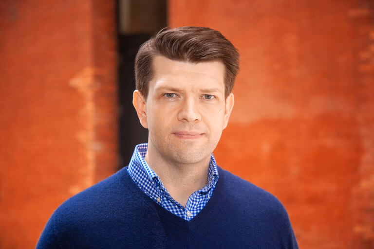 Young professional posing for LinkedIn headshot in NYC studio with natural lighting